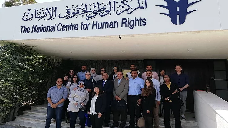 The photograph shows the National Centre for Human Rights (المركز الوطني لحقوق الإنسان) in Amman, Jordan. Participants are posing for a group photograph in front of the entrance.